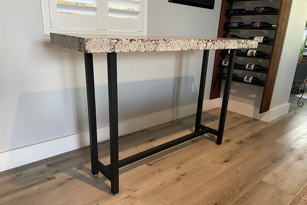 Concrete table next to wine rack, an example of our Somis handcrafted concrete furniture.